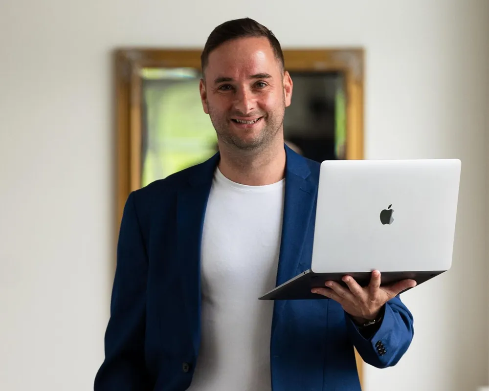 Immobilienmakler Felix Berger stehend mit einem Laptop